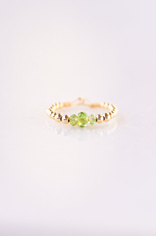 Minimalist beaded ring with faceted peridot and gold beads, showcasing elegant and delicate design