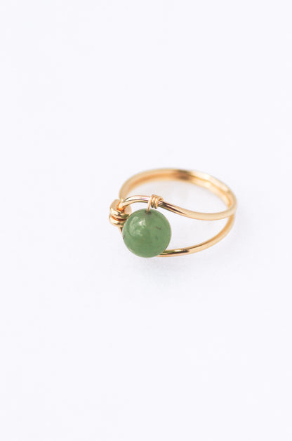 Sustainable  Gold ring with a green gemstone on a white background