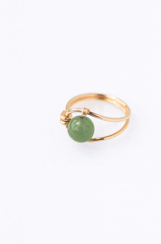 Sustainable  Gold ring with a green gemstone on a white background