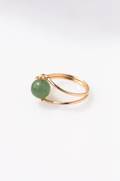 Sustainable Gold ring with a green gemstone on a white background