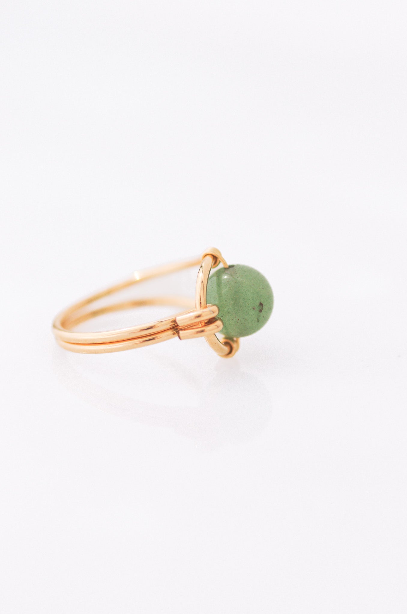 Sustainable Gold ring with a green stone on a white background