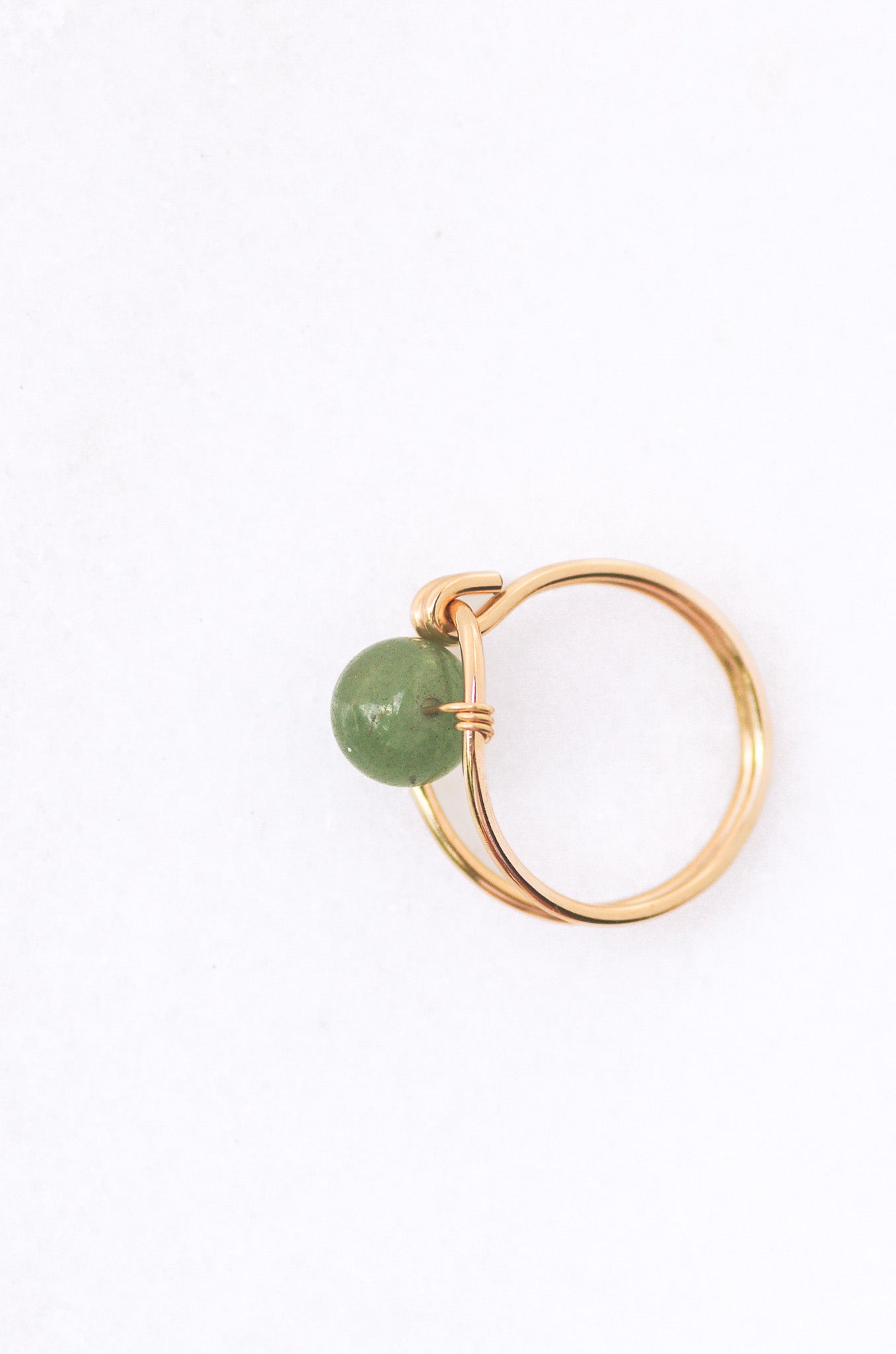 Sustainable Gold ring with a green gemstone on a white background