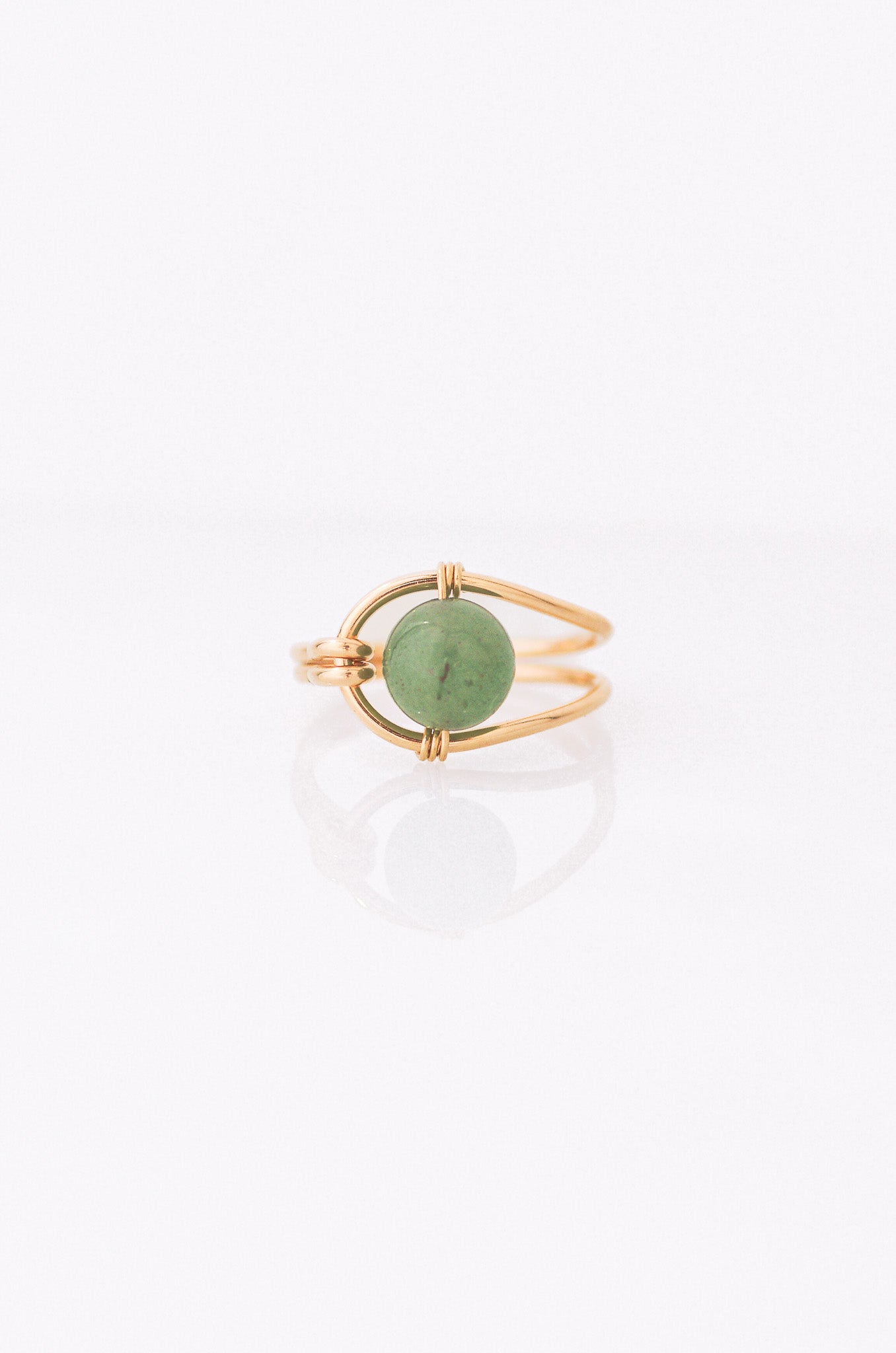 Sustainable Gold ring with a green gemstone on a white background