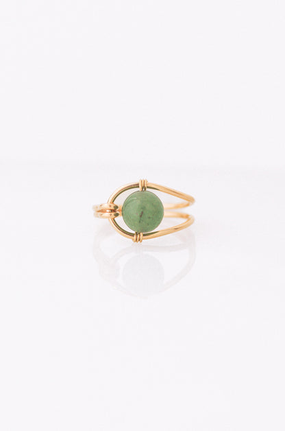 Sustainable Gold ring with a green gemstone on a white background